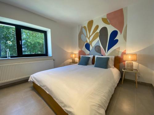 a bedroom with a large bed with a painting on the wall at Le Veenbahn in Deidenberg