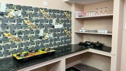 a kitchen with a stove and a tile wall at SK VILLA in Puducherry