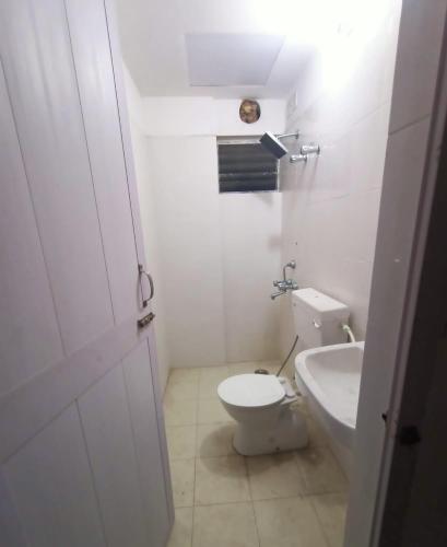 a white bathroom with a toilet and a sink at Nest in Khardah