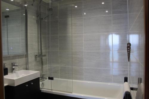 a bathroom with a tub and a sink and a shower at Apartment 19 in Downderry