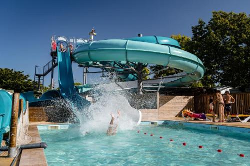 une personne dans une piscine avec toboggan dans l'établissement Mer et Soleil 5 étoiles à Oléron empl 170 3CH 1SDB 8 personnes, à Les Sables Vignier