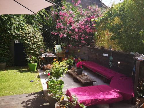 un jardin avec un canapé rouge et quelques fleurs dans l'établissement Studio avec kitchenette salle de bain et wc partagé, à Toulon