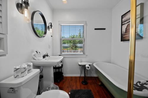 a white bathroom with a tub and a sink and a bath tub at Happy Hours - Modern Cabin with Game Room and Peek-a-Boo Lake Views! in Big Bear Lake