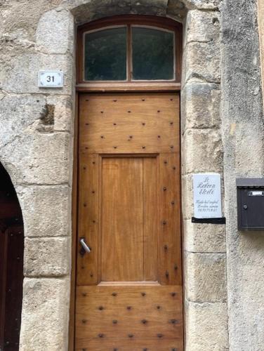 une porte en bois dans un bâtiment en pierre avec un panneau dessus dans l'établissement Le balcon étoilé, à Moustiers-Sainte-Marie