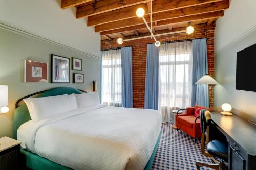 a bedroom with a bed and a desk and a couch at Trilogy Hotel Montgomery, Autograph Collection in Montgomery