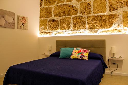 ein Schlafzimmer mit einem Bett vor einer Steinwand in der Unterkunft Holiday Home MATT ROS in Noto
