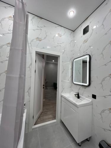 a white bathroom with a sink and a mirror at Sairam-16 уютная квартира Nurly zhol in Promyshlennyy