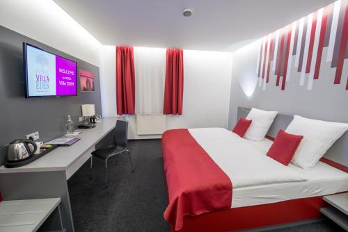 a hotel room with a bed and a desk and a tv at Hotel Villa EDEN in Jihlava