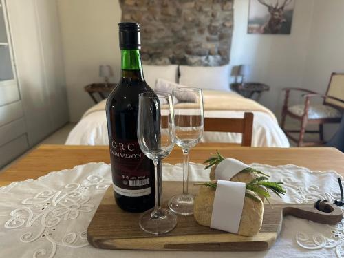 a bottle of wine and two glasses on a table at Dagbreek Cottages in Keimoes
