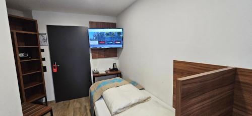 a small room with a bed and a tv on the wall at Hotel Villa Sophia in Cologne