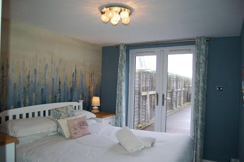 a bedroom with a bed and a window with a view at Sound of the Sea, beach front Bungalow with hot tub, in Tywyn in Tywyn
