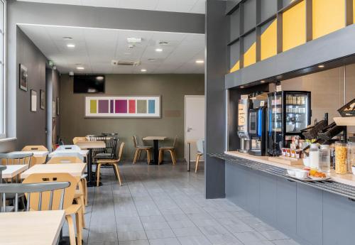 a restaurant with tables and chairs and a counter at B&B HOTEL Lille Roubaix Campus Gare in Roubaix