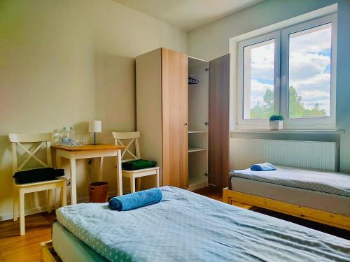 a room with two beds and a desk and a window at Dom Bez Ścian in Gubin