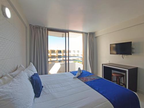 a bedroom with a bed with a large window at Hotel Margarita Dynasty in Porlamar