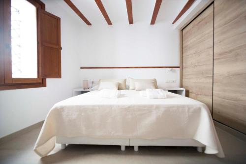 a white bedroom with a large white bed with a window at Apartamentos Turísticos La Bodegueta in Utiel