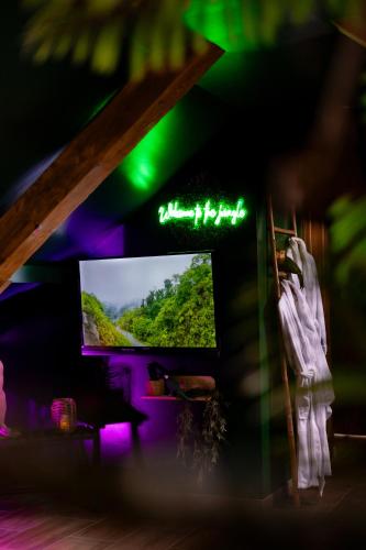 a room with a tv and a sign on the wall at Dynasty Jungle Home Spa Jacuzzi in Holtzheim