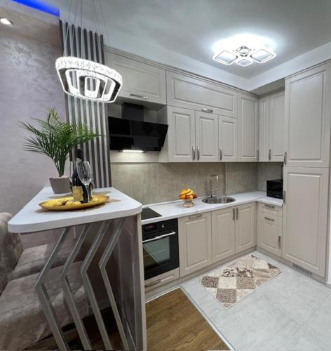 a kitchen with white cabinets and a island in it at Imperial Lux Apartment in Kragujevac