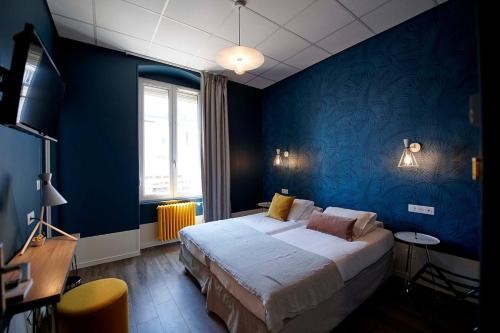 a bedroom with a large bed and a blue wall at H&ocirc;tel de France - Beaune in Beaune