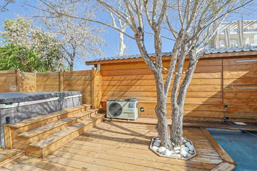 a tree sitting on a deck next to a fence at Maison avec Piscine et Jacuzzi Proche des plages in Toulon