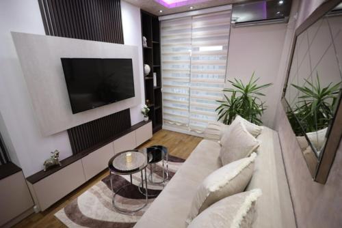 a living room with a white couch and a tv at Imperial Lux Apartment in Kragujevac