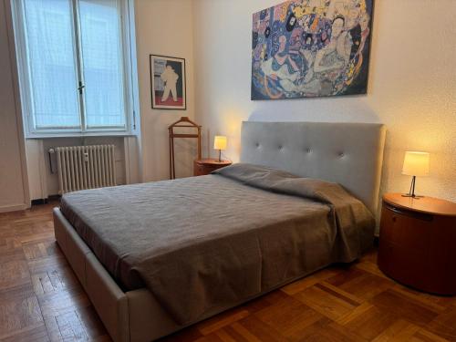 a bedroom with a bed with two lamps and a painting at Casa Rosy Como Historic Centre in Como