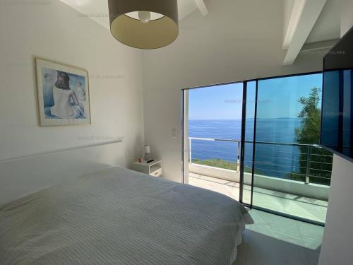 une chambre avec un lit et une grande fenêtre en verre dans l'établissement Belle villa à Cavalaire-sur-Mer avec piscine et vue mer - FR-1-100-228, à Cavalaire-sur-Mer