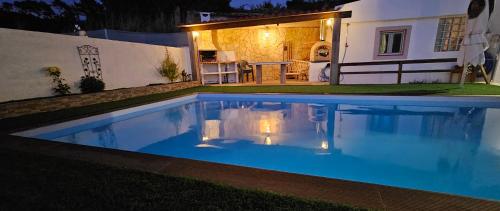 a swimming pool in front of a house at night at Casa do Aconchego em Freiria in Freiria