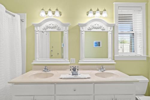 a bathroom with two sinks and two mirrors at La Valencia Villas in Rosemary Beach