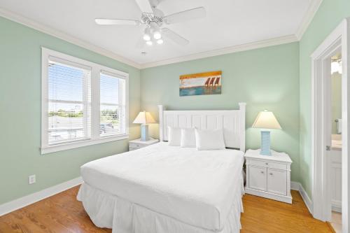 a bedroom with a white bed and two windows at La Valencia Villas in Rosemary Beach