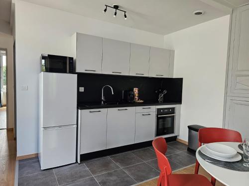 une cuisine avec des appareils blancs et une table avec des chaises rouges dans l'établissement Aux'Cerfs - A deux pas de l'Abbaye, à Auxerre