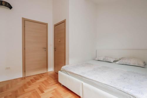 a white bedroom with a white bed and wooden floors at Duplex 3 bedrooms on the first line in Petrovac in Petrovac na Moru