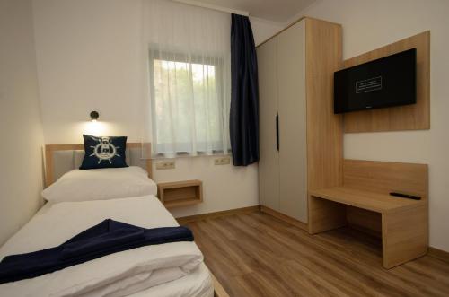 a bedroom with two beds and a flat screen tv at Riverside Apartmanház Gyula in Gyula