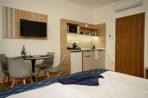 a bedroom with a bed and a table and a kitchen at Riverside Apartmanház Gyula in Gyula
