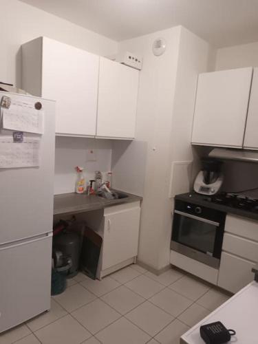 une petite cuisine avec des armoires blanches et une cuisinière dans l'établissement Appart Elégant JO Ctre Ville Transport Proche CDG Parc d'exposition, à Les Pavillons-sous-Bois
