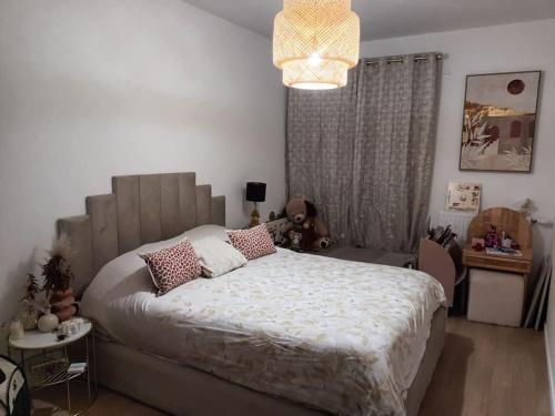 une chambre avec un grand lit et un lustre dans l'établissement Appart Elégant JO Ctre Ville Transport Proche CDG Parc d'exposition, à Les Pavillons-sous-Bois