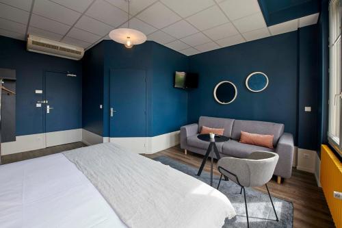 a bedroom with blue walls and a bed and a couch at Hôtel de France - Beaune in Beaune