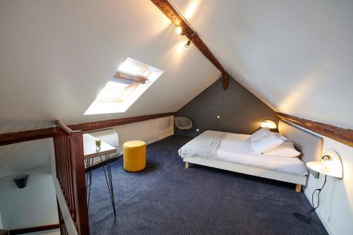 a attic bedroom with a bed and a skylight at Hôtel de France - Beaune in Beaune