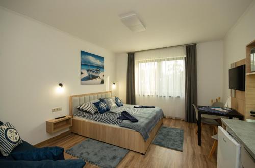 a bedroom with a bed and a couch and a television at Riverside Apartmanház Gyula in Gyula