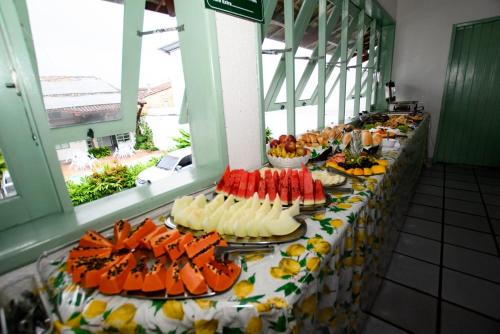 a buffet line with plates of food on a table at Hotel Porto Verde -JG in Porto Seguro