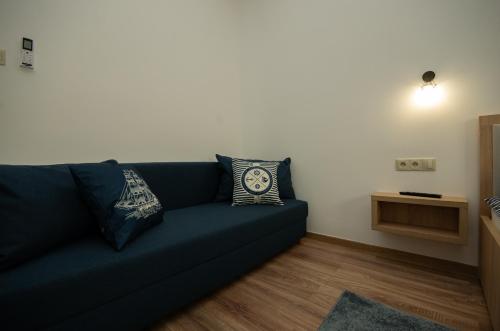 a living room with a blue couch with pillows at Riverside Apartmanház Gyula in Gyula