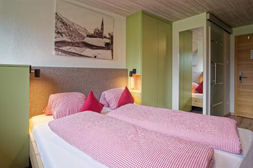 a bedroom with a large bed with pink pillows at Bergchalet Hotel Reinerhof in Riva di Tures