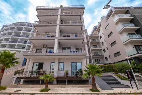 an apartment building with palm trees in front of it at Franklin Rooms in Sarandë