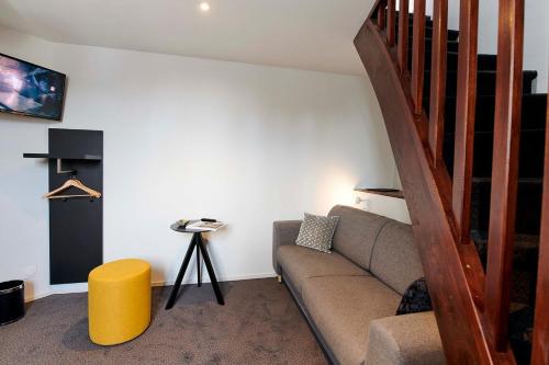 a living room with a couch and a staircase at Hôtel de France - Beaune in Beaune