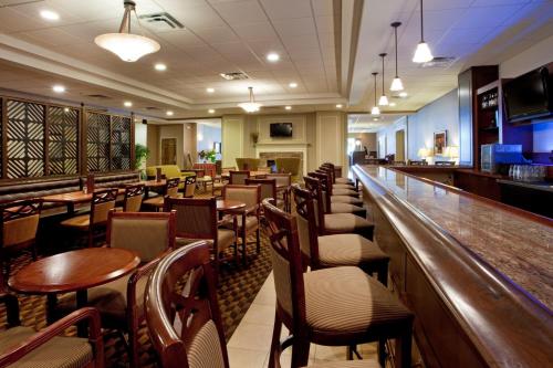 a restaurant with a bar with tables and chairs at Holiday Inn University Area Charlottesville by IHG in Charlottesville