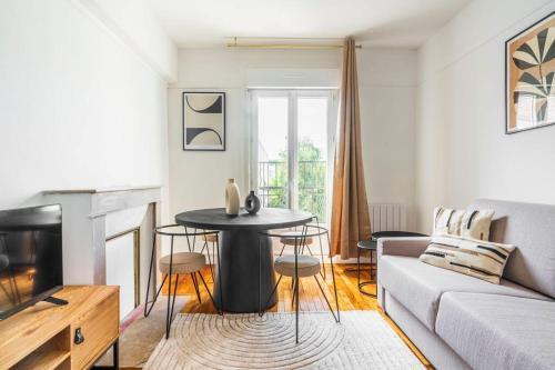 un salon avec une table et un canapé dans l'établissement Appartement Neuf Banlieue Parisienne - Montreuil, à Montreuil