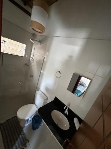 Un baño con inodoro, lavabo y espejo. en Recanto Mucugê, en Porto Seguro