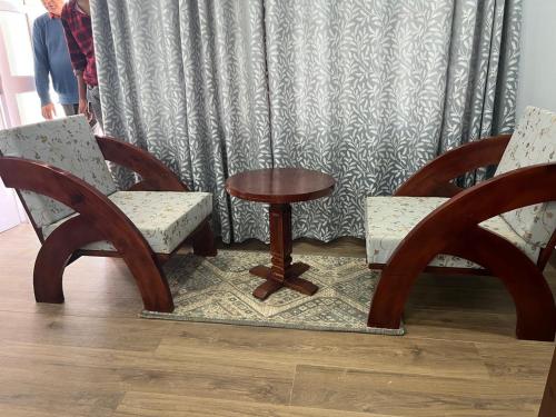 two chairs and a table in front of a curtain at The Whitegrove Retreat in Mukteswar