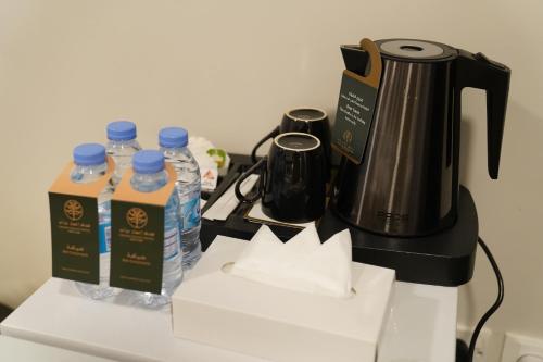 a counter with a coffee maker and bottles of water at Emaar Andalusia in Makkah