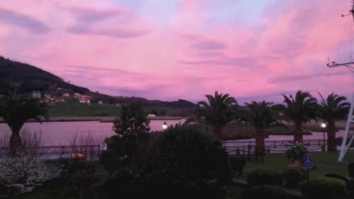a view of a lake at sunset with palm trees at Vegalmar in Limpias