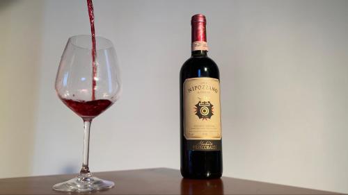 a bottle of red wine next to a glass at Stone house in Larciano